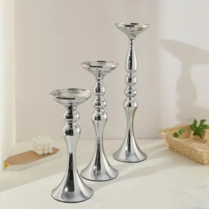 Three silver candle holders on a table.